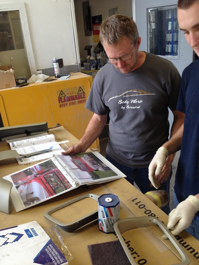 Master repairmen discussing the headlight cover color while looking at stills.